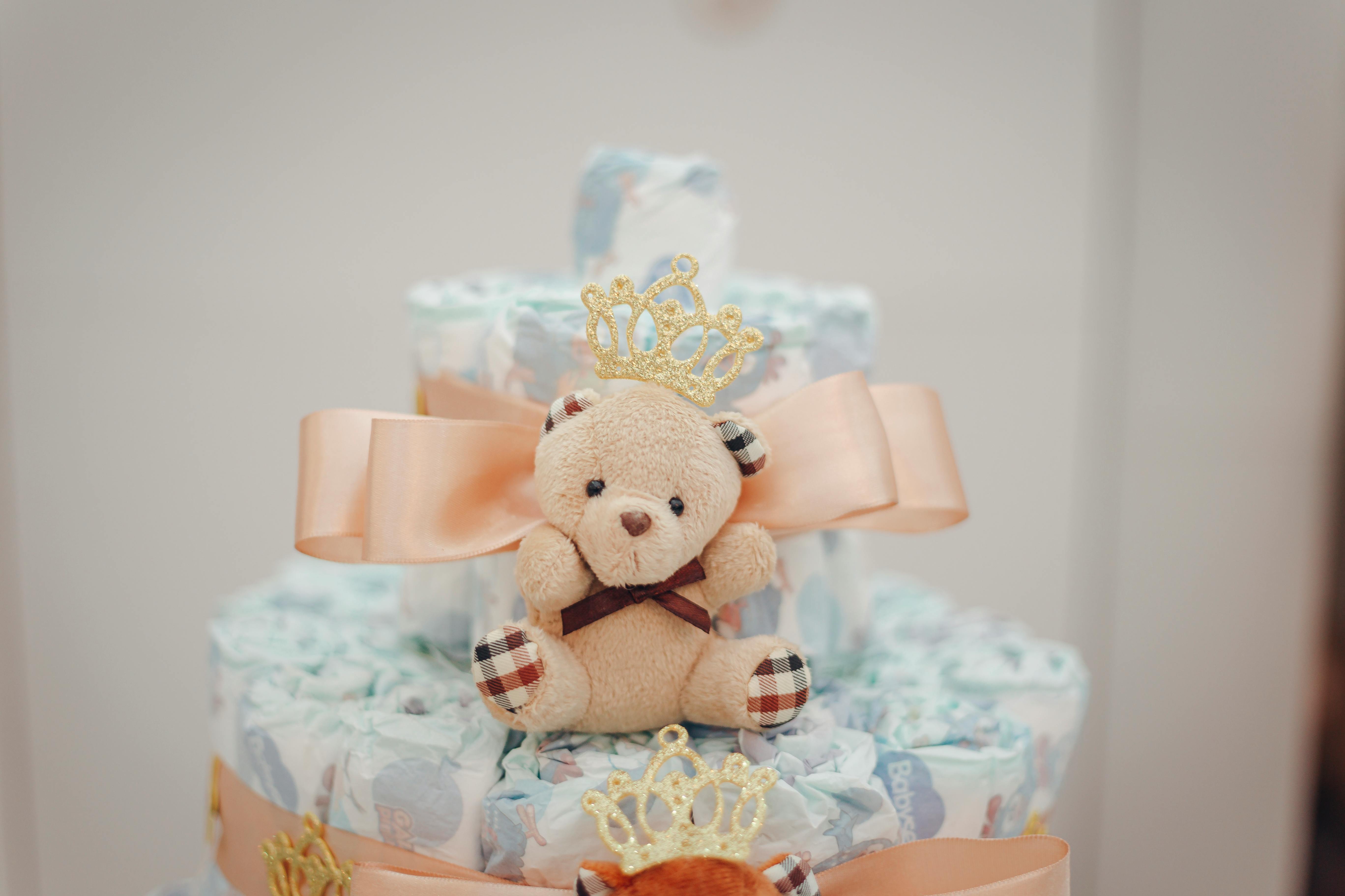Delightful diaper cake adorned with a cute teddy bear and peach bow, perfect for baby showers.