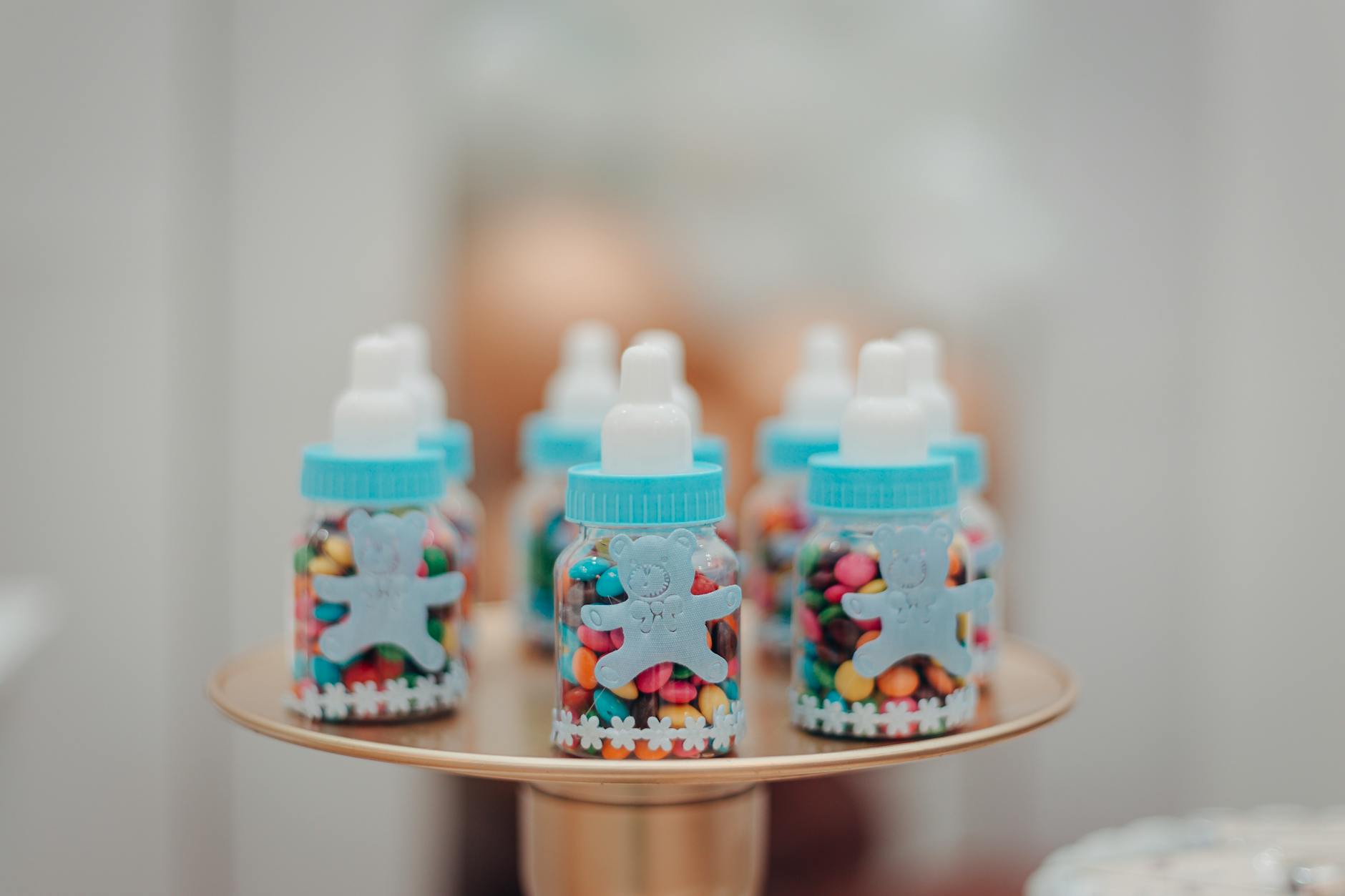 Vibrant candies in baby bottles on a tray, perfect for a baby shower or kids' party.