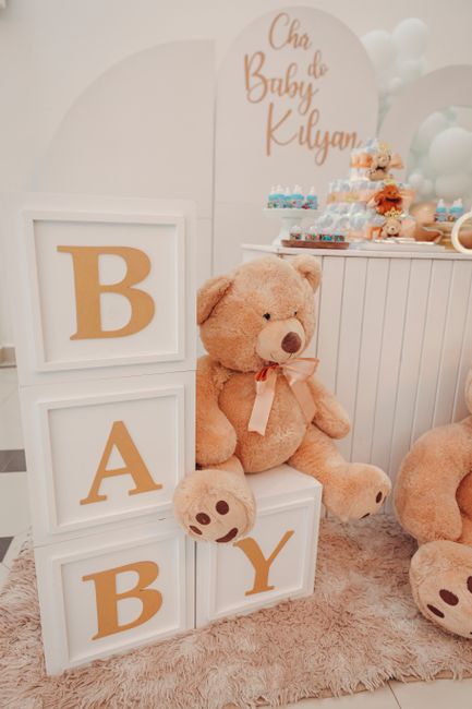 Fotomural Encantadora decoración para un baby shower con un gran oso de peluche y bloques de letras que deletrean 'BABY'.