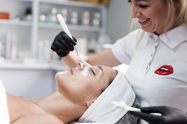 Beautician Covering Woman Face With White Cosmetic Clay