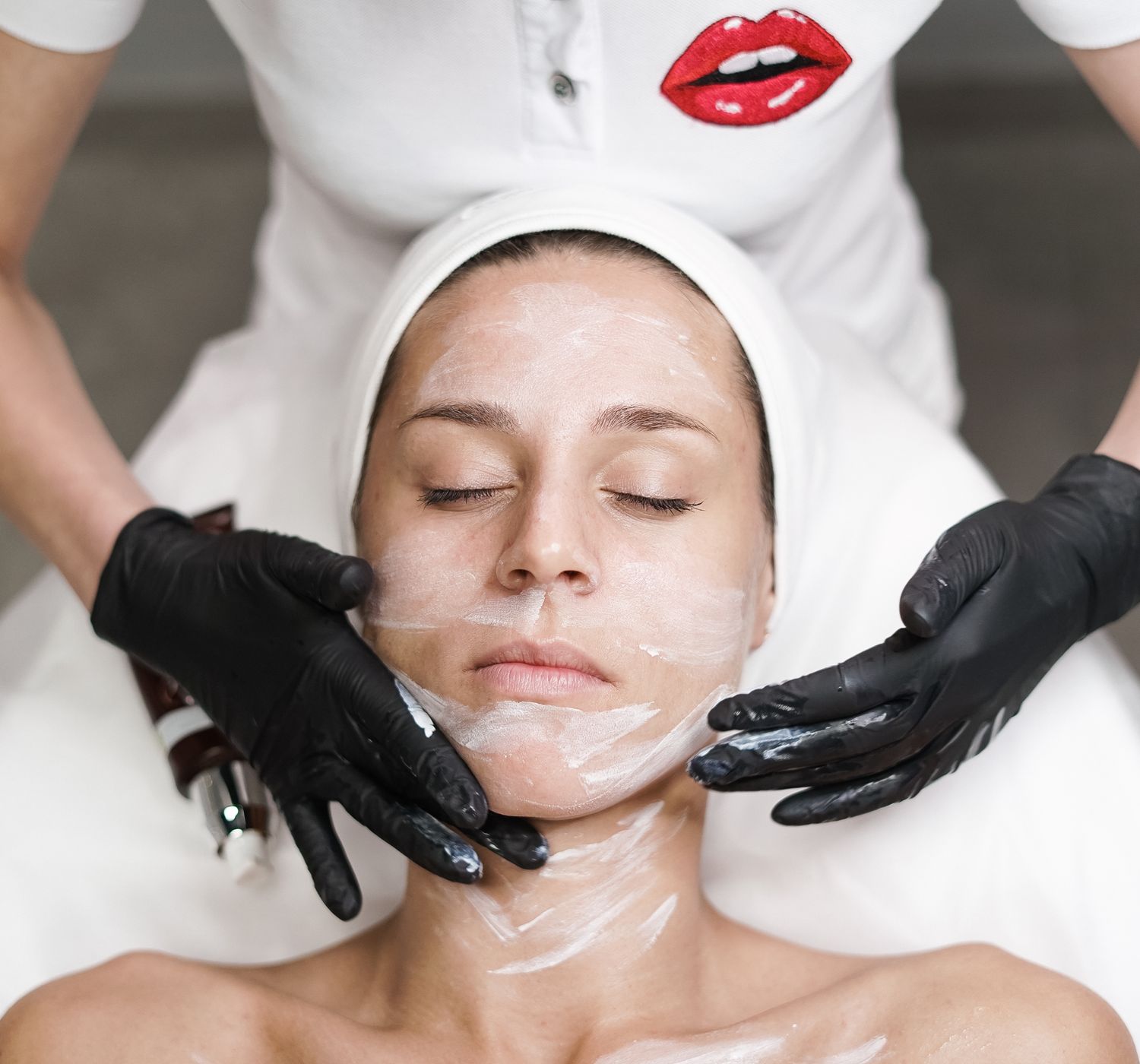 Woman receiving a facial treatment at spa, with beautician applying mask in a relaxing set