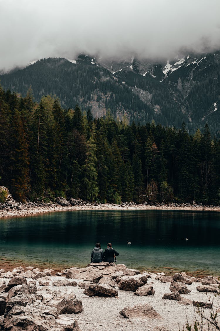 Couple Sitting On Rock Near Lake