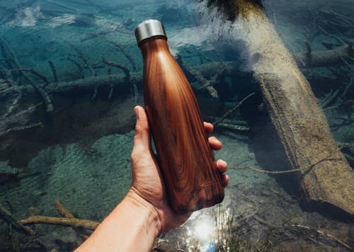 Person Holding Brown Wooden Bottle