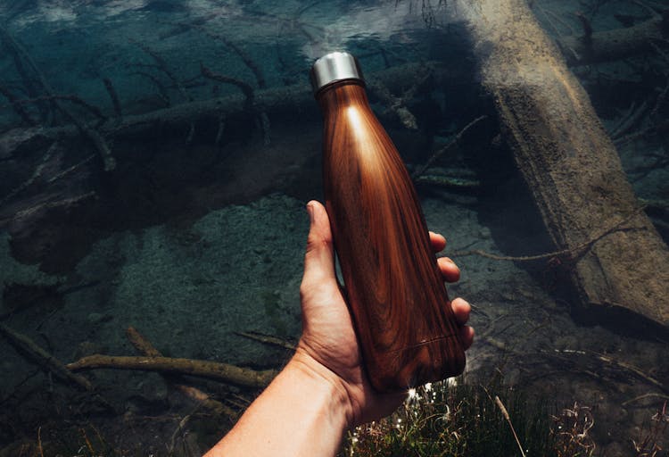 Hand Holding A Wood Grain Thermal Water Bottle