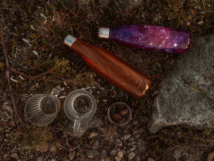 Water Bottles On Brown Grass Beside Glass Cups