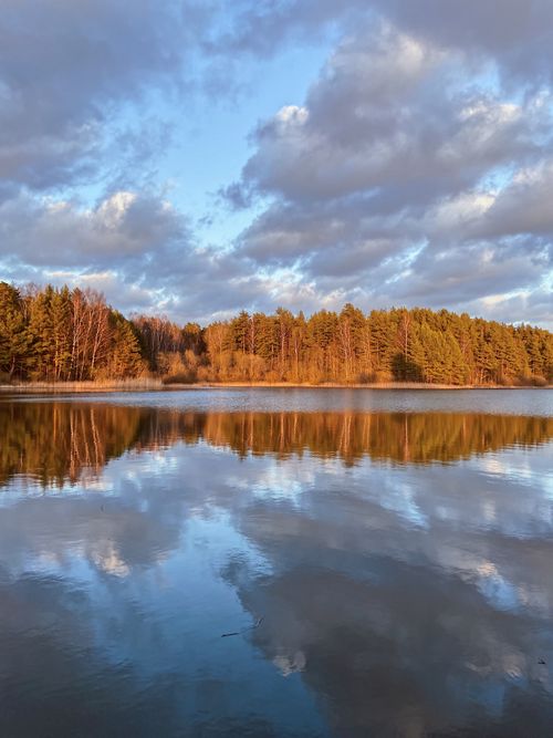 Free Tranquil scene of a lake reflecting a forest under a vibrant sunset sky. Stock Photo
