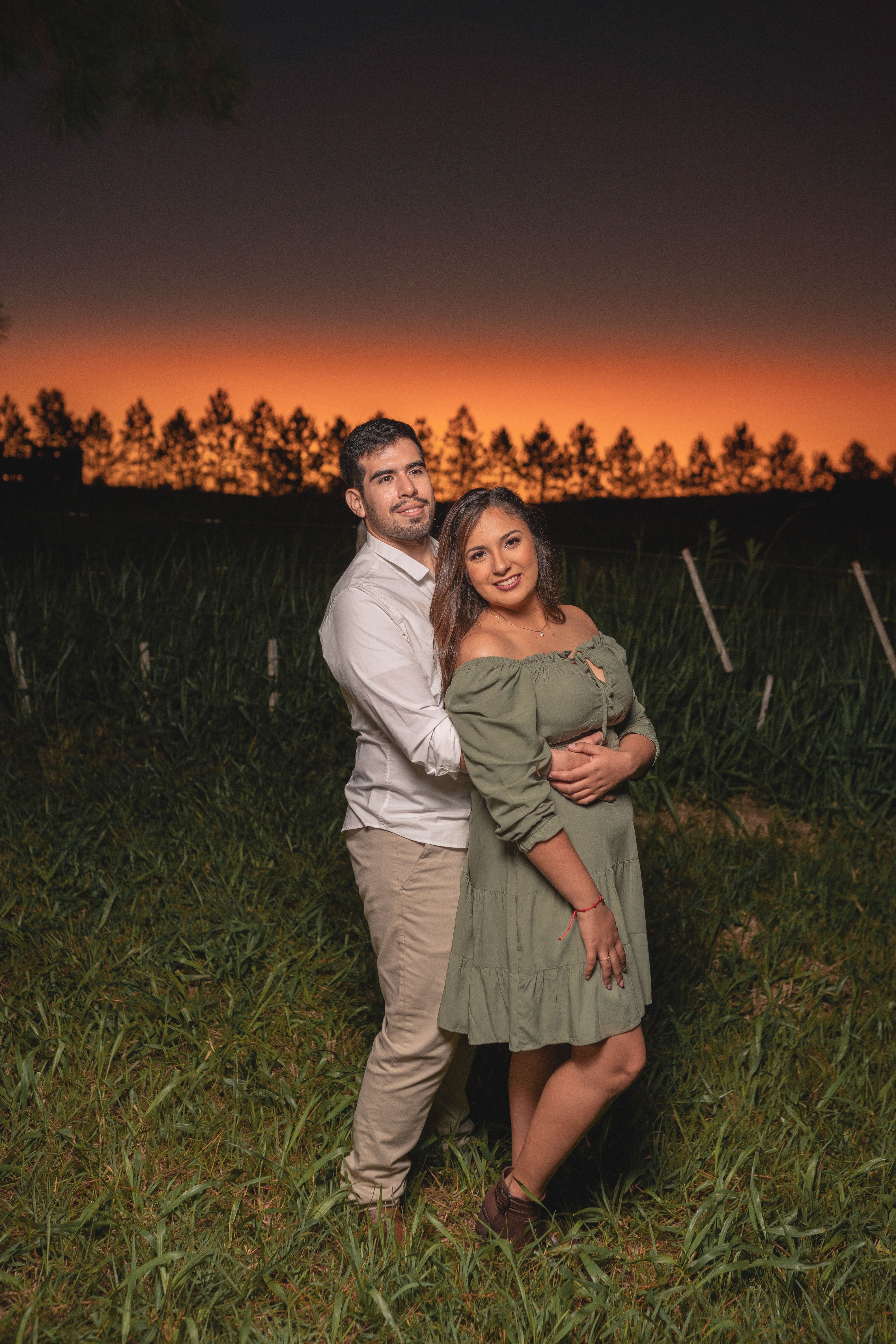 A couple embracing in a field at sunset, showcasing love and affection.
