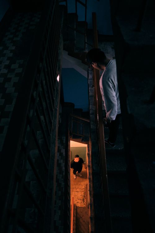 Free High-angle view of two men on dimly lit staircase creates a mysterious ambiance. Stock Photo