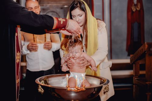 Free A traditional baby baptism ceremony inside a church with priest and family present. Stock Photo