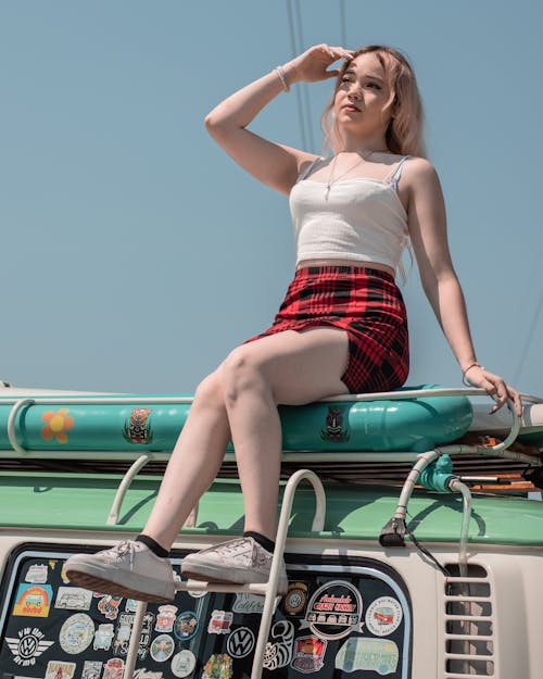 Woman in White Tank Top Sitting on the Roof of a Van