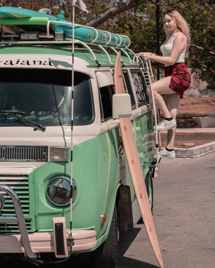 Woman Climbing On Ladder Of Green Van