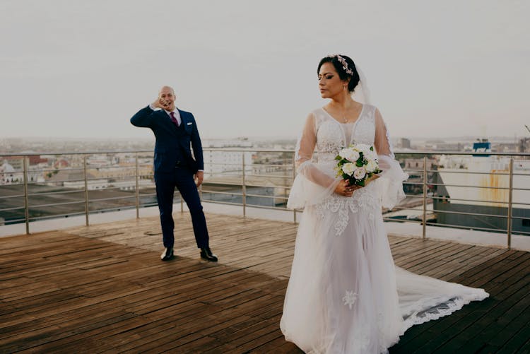 Man In Black Suit Standing Beside Woman In White Wedding Dress