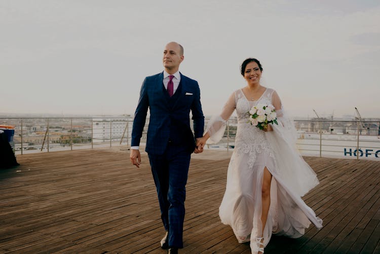 Bride And Groom Walking On Wood Deck