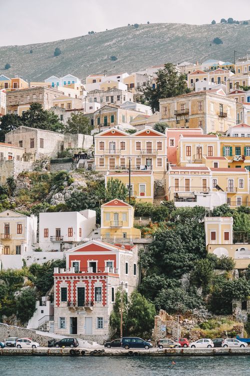Free Charming colorful houses on a green hillside in Symi, Greece, showing Mediterranean architecture. Stock Photo