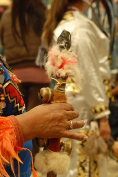 Close-up of a hand holding bells during a Native American ceremony.