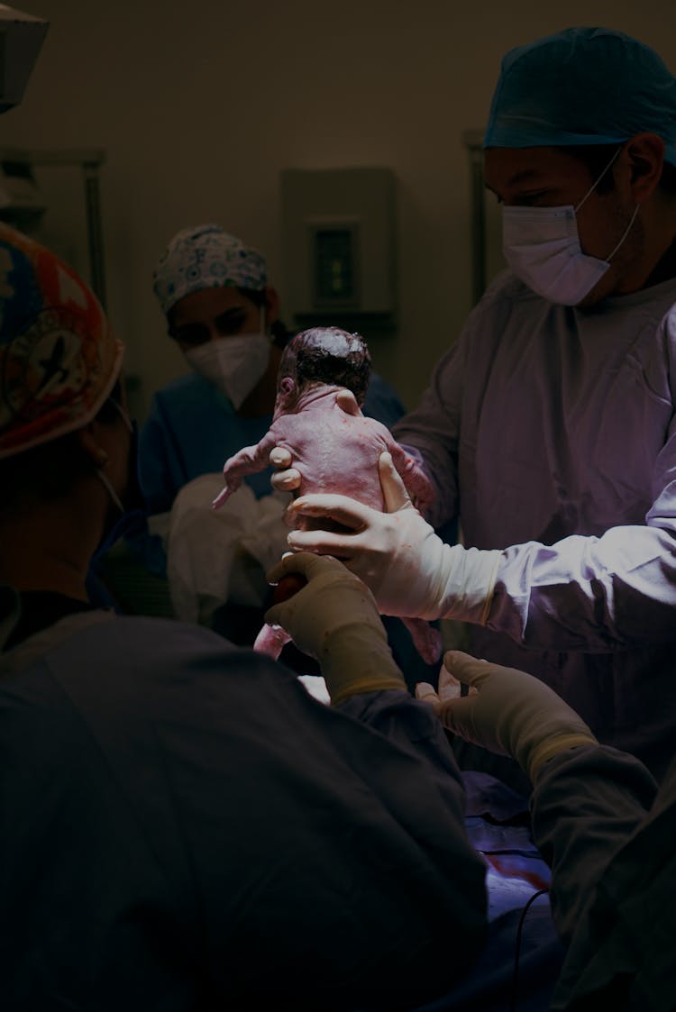 Doctor And Nurses Holding Newborn Baby Just After Labor