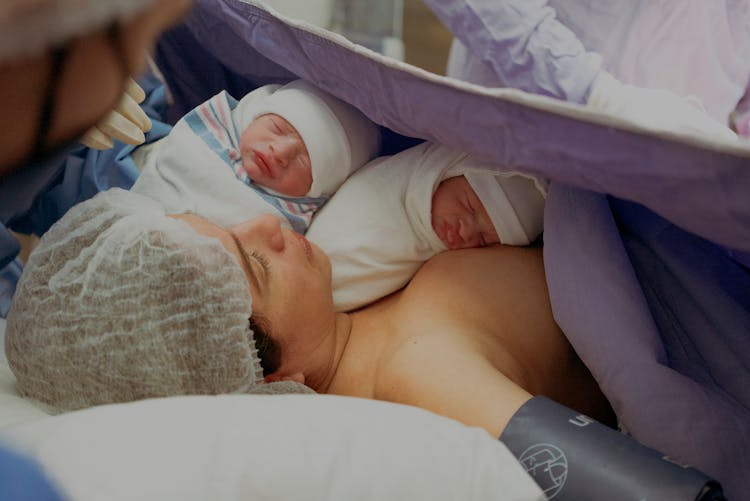 Woman With Her Newborn Twins On A Hospital Bed