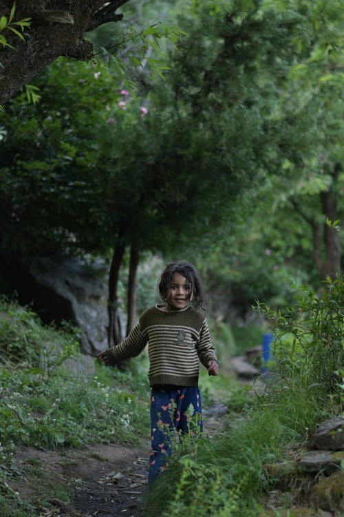 Little Girl in Striped green Sweater Walking on Unpaved Path