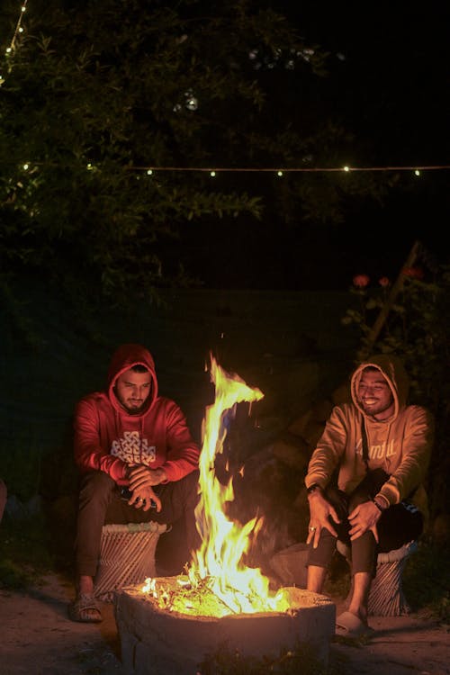 Men in Hoodie Sweaters Sitting Beside a Bonfire