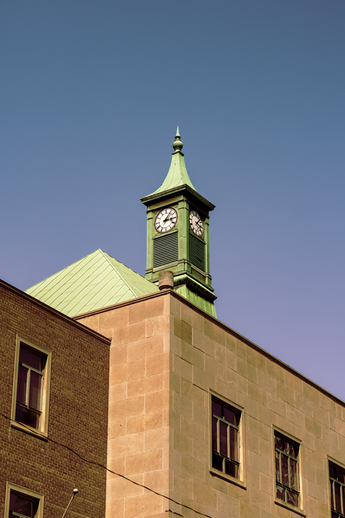 Free A charming green clock tower rises against a clear blue sky in Toronto, Canada. Stock Photo