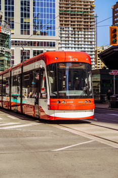A red streetcar traveling through downtown Toronto, showcasing urban transportation.