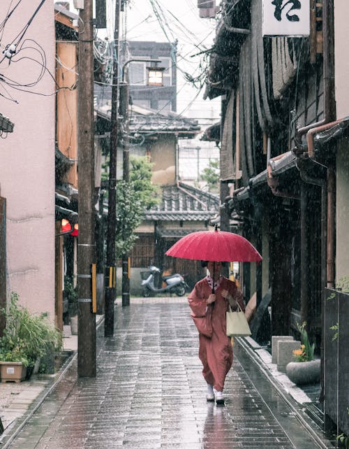 콘크리트 통로에 걷고 우산을 들고 갈색 가운에 여자