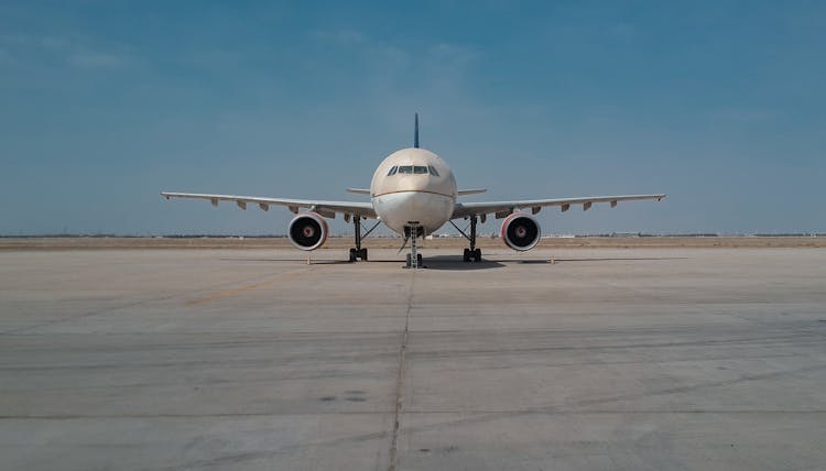 Front View Of An Airplane On Tarmac Under Blue Sky