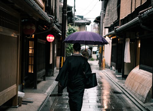 Free Woman Using Purple Umbrella Walking in the Street Stock Photo