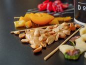 Close-up of assorted fruits, nuts, and peanut butter on skewers, showcasing a vibrant, healthy snack.