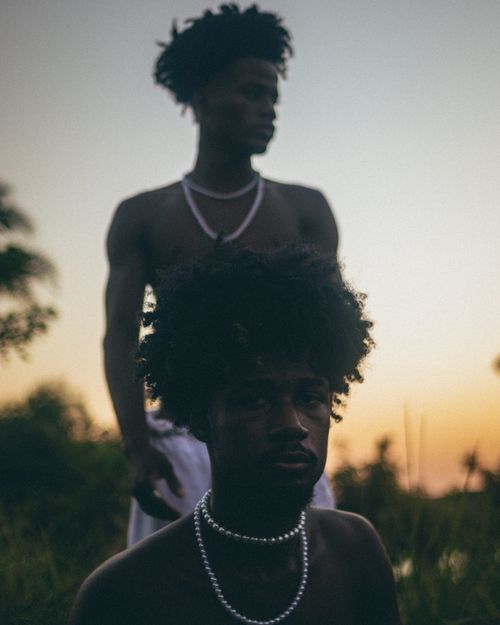 Free Artistic silhouette of shirtless men wearing necklaces at sunset in Madre de Deus, Brazil. Stock Photo