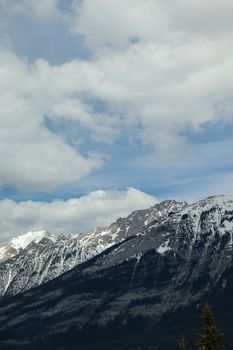 Majestic view of snow-capped Rocky Mountain with dramatic clouds overhead.