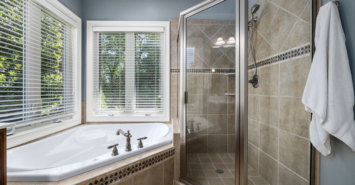 Elegant bathroom with glass shower, soaking tub, and large windows offering natural light.