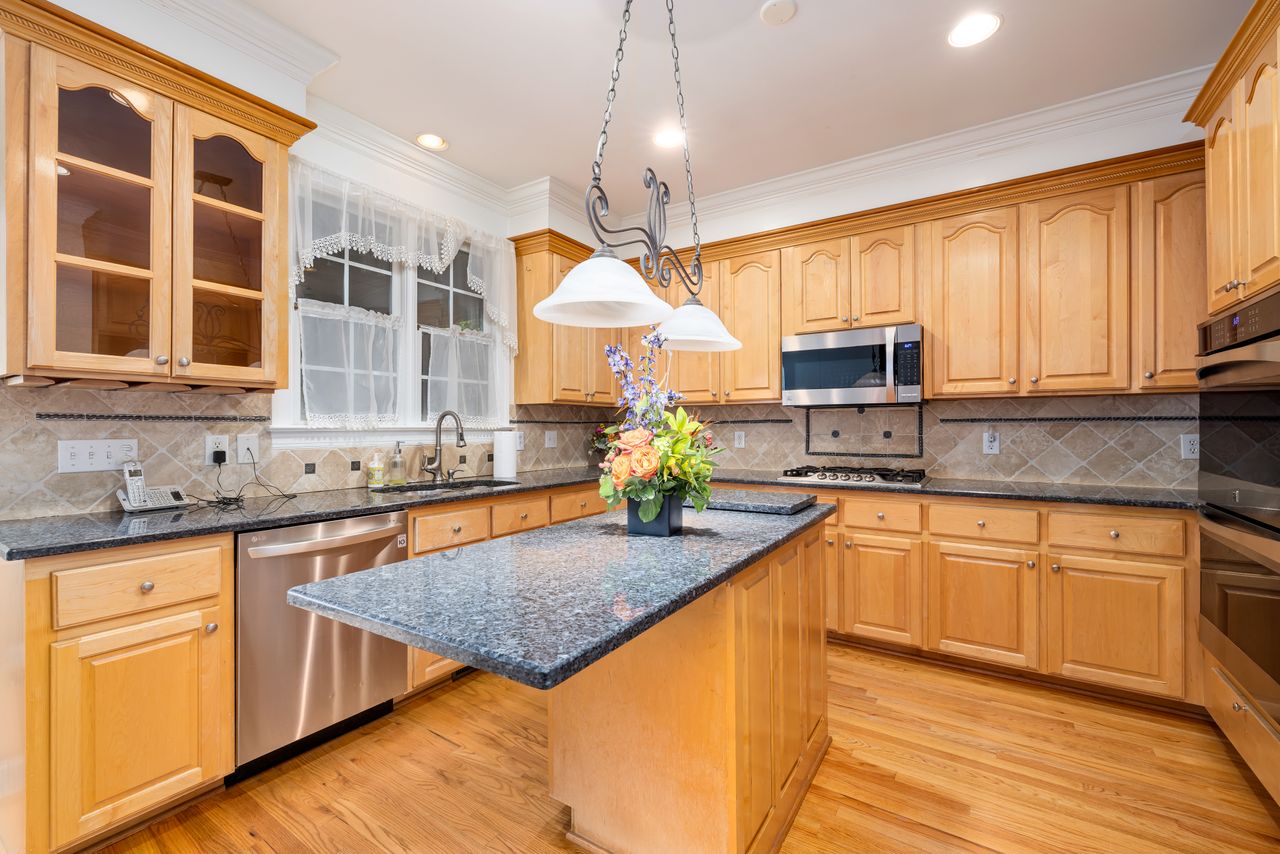 white-cabinets-wood-accents Kitchen with wooden cabinets and light stone countertops