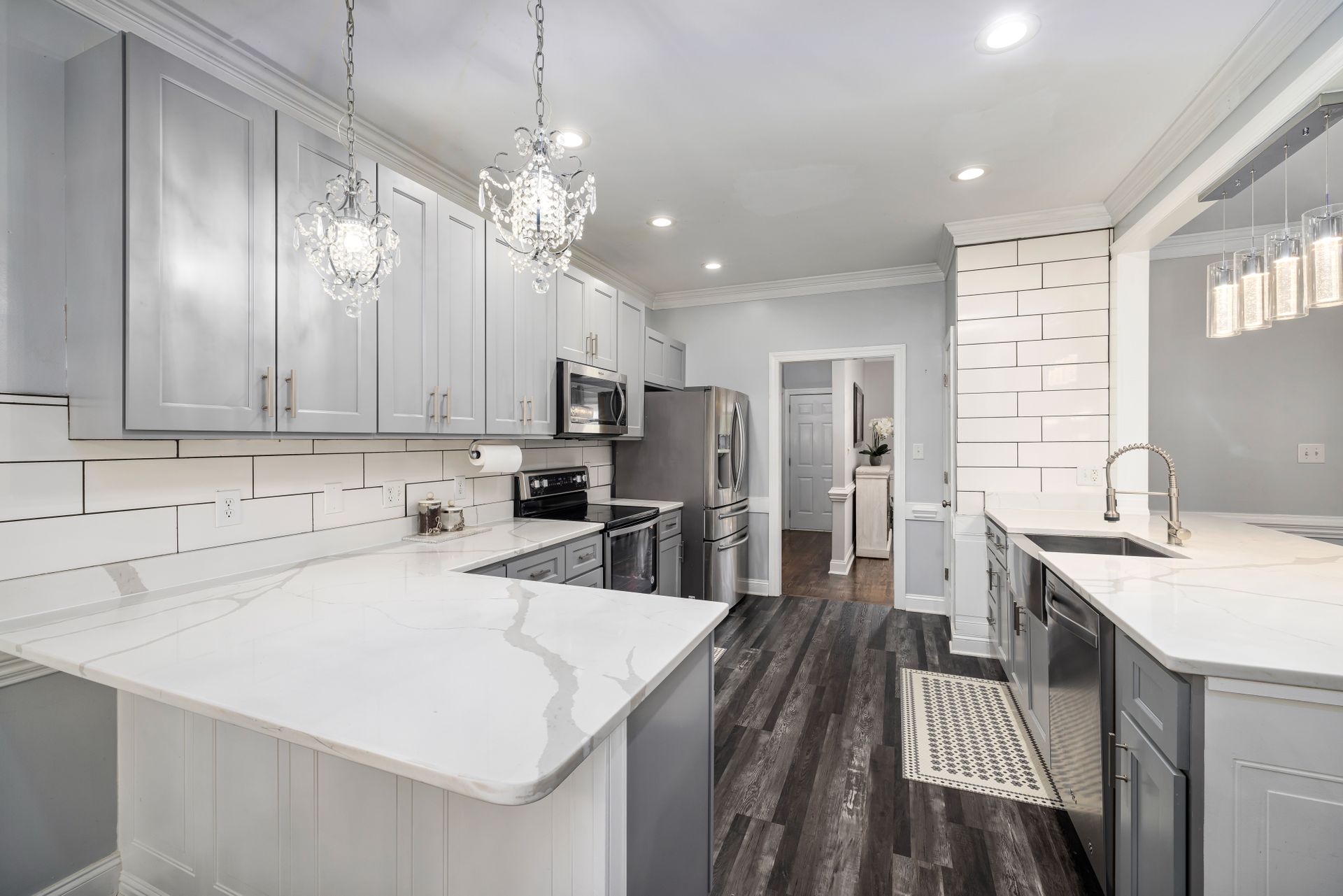 Spacious contemporary kitchen featuring marble counters and elegant lighting.