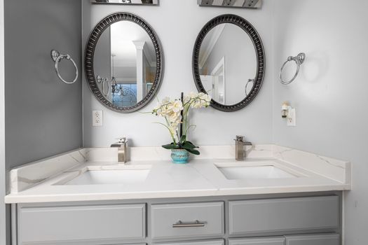 Elegant bathroom with dual sinks, mirrors, and a marble countertop featuring contemporary fixtures.