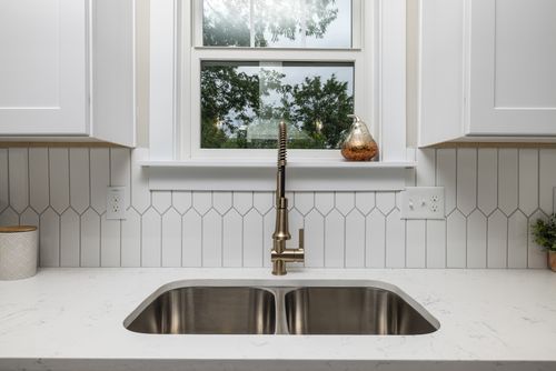 Free Contemporary kitchen design featuring white cabinets and a stainless steel sink with a minimalist faucet. Stock Photo