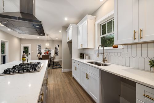 Free Elegant modern kitchen with white cabinets and dining space, showcasing minimalist interior design. Stock Photo