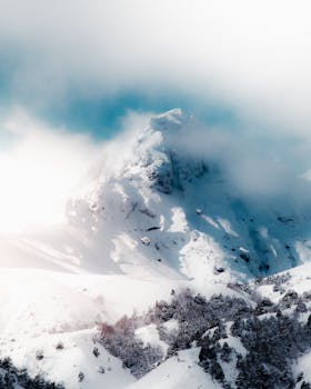 A stunning view of a snow-covered mountain peak enveloped in clouds in Chile's winter landscape.