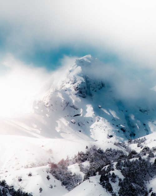 Free A stunning view of a snow-covered mountain peak enveloped in clouds in Chile's winter landscape. Stock Photo