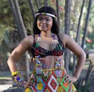 一位身着鲜艳祖鲁服装的年轻女子在户外自信地微笑着摆姿势