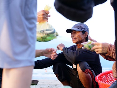 A Fish Vendor Crouching on the Ground  