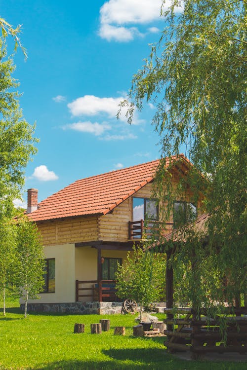 Casa Pintada De Marrón Y Beige Rodeada De árboles Y Campo De Hierba