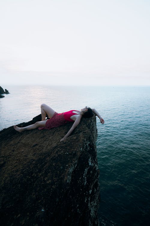 Woman Lying Down on Rock on Sea Shore