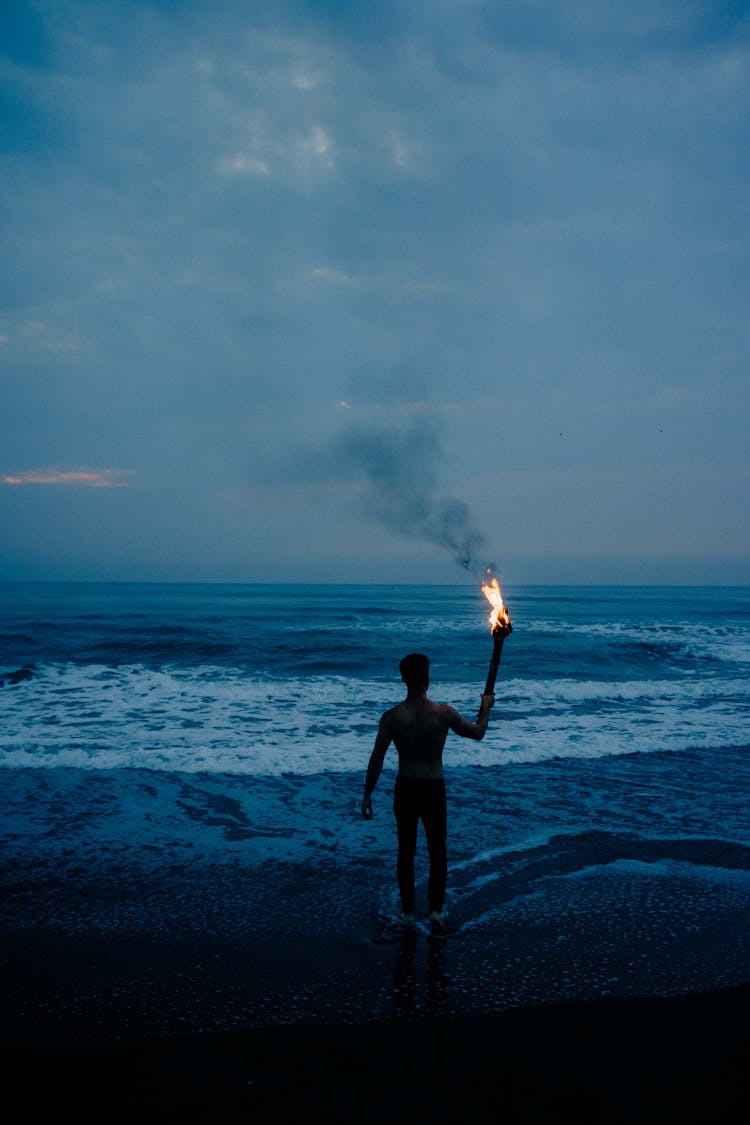 Man Walking Into The Sea With A Torch In His Hand