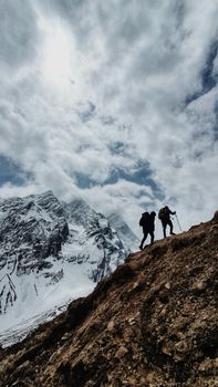 Two hikers trek along a snowy mountain in Nepal's scenic landscape.