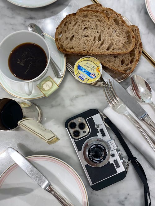 Bread with Coffee and a Digital Camera on a White Sheet 