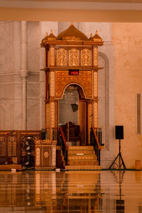 Free Ornate interior of a mosque in Indonesia featuring a wooden minbar and prayer clock. Stock Photo