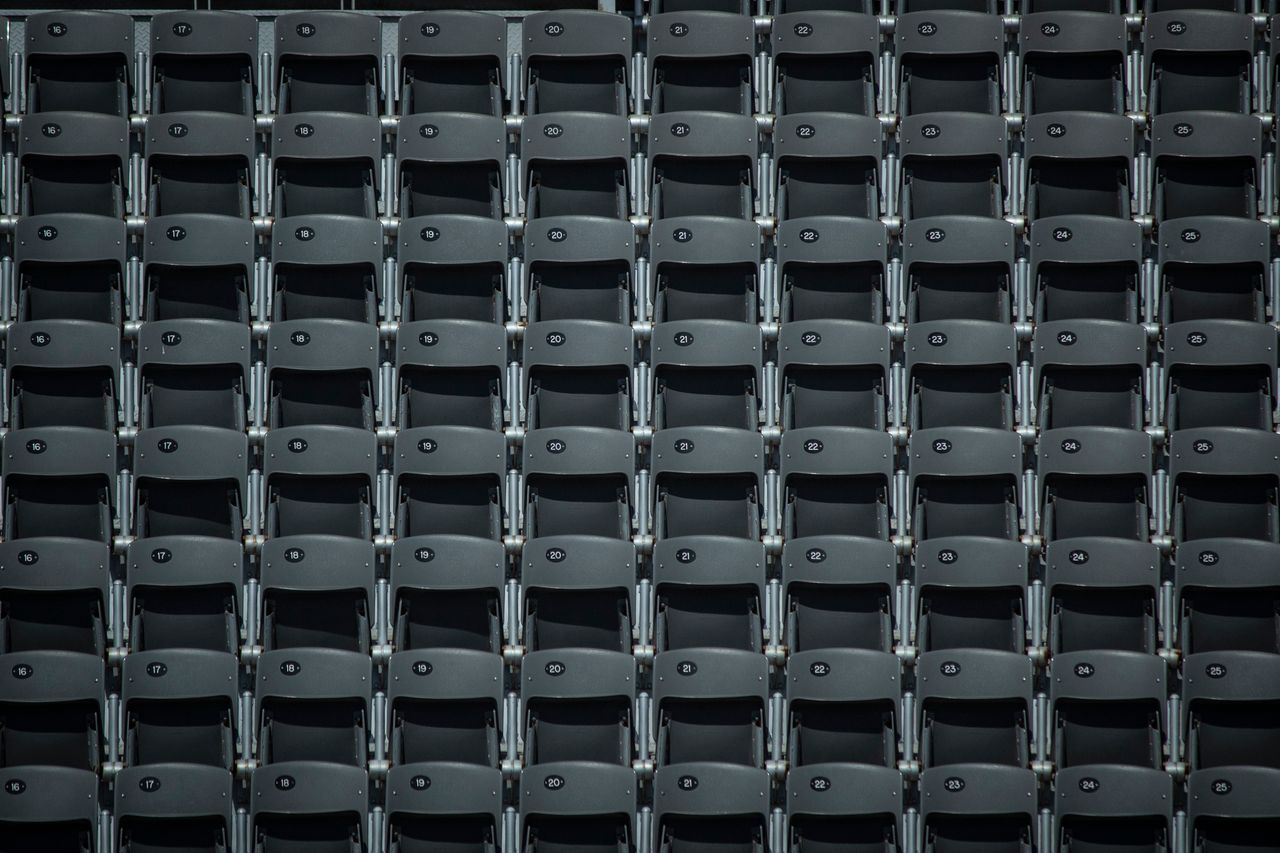 symmetrical rows of empty gray seats in an indoor stadium or auditoriu