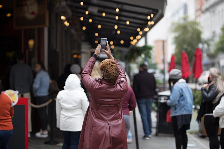 Back Of A Woman Taking Photos With Her Phone