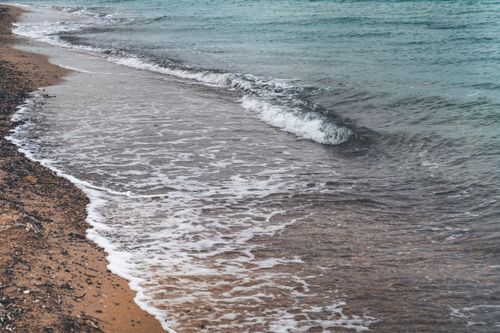Free Calm ocean wave gently hitting the sandy beach shore in Edirne, Turkey. Stock Photo